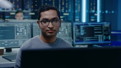 Portrait of a Smart and Handsome Software Developer Wearing Glasses Working on a Personal Computer,