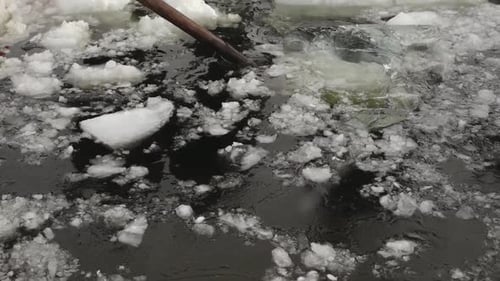 Close-up of tools breaking and clearing ice from a frozen lake, creating an ice hole in winter