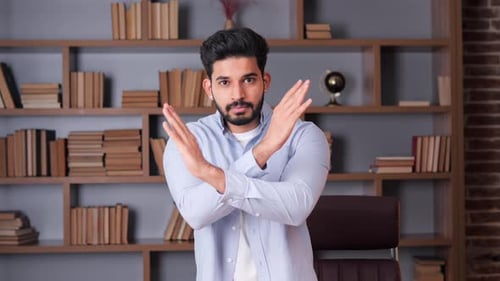 Indian Man in a Blue Shirt Making a Stop or Don't Do It Gesture in an Office