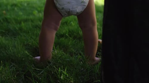 Infant Taking First Steps on Green Grass