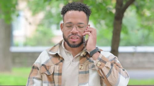 Multi Ethnic Man Talking on a Smartphone in a Park