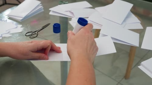 Closeup Hand View of Applying Glue to Folded Paper in Paper Craft Project