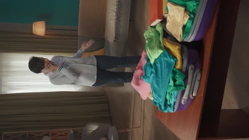 Vertical Video of a Brunette Middleaged Woman Having a Call on the Background While Packing a