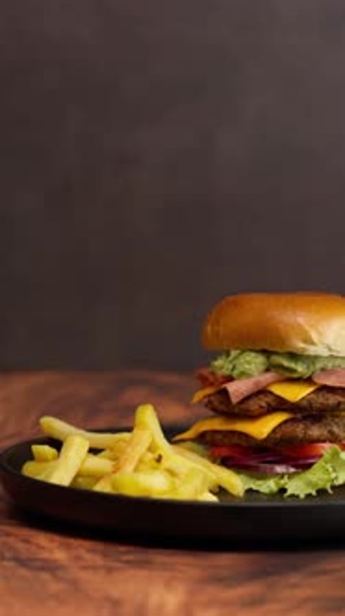 Mexican Double Meat Burger With Guacamole And French Fries On A Black Plate