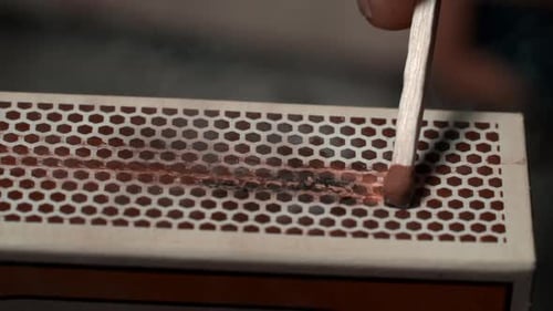 Close Up of Match Lighting Against Matchbox