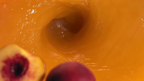 Super Slow Motion Shot of Fresh Peaches Falling Into Juice Whirl