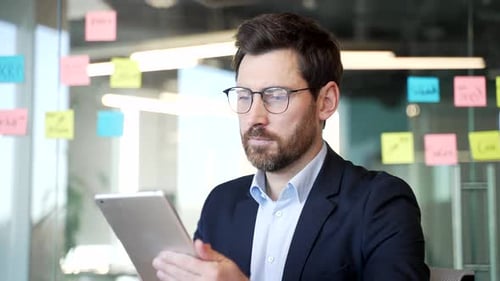 Businessman in a formal suit is using digital at workplace in business office. Manager works