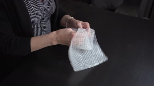 Bored female office worker pops some bubble wrap to relieve the boredom.