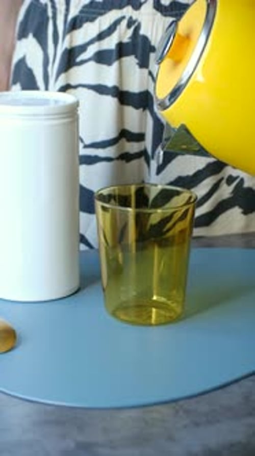 Water Being Poured into Glass on Blue Surface