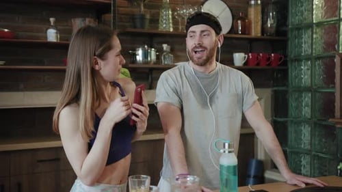 Fit Couple Listening Music, Drinking Juice in Kitchen