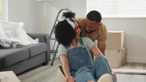 Black couple, real estate and fun moving into new home playing with boxes and laughing at home