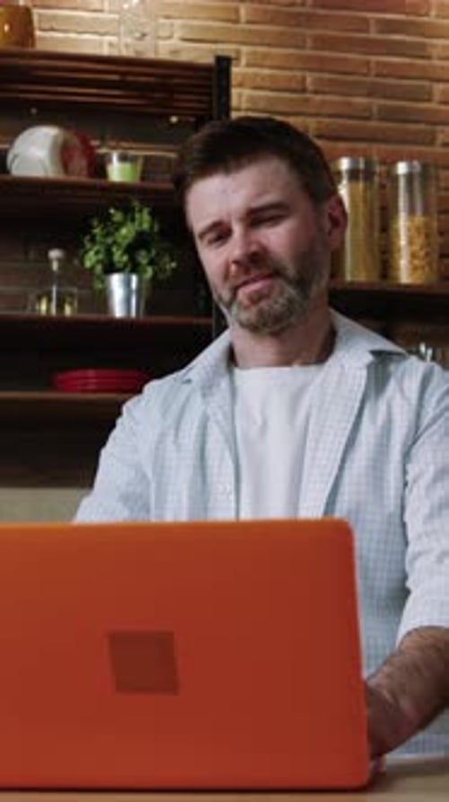 A Focused Man Is Deeply Engaged Working on His Laptop While in a Modern Kitchen Setting