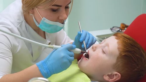 Closeup of Female Dentist Treating Little Boy in Dental Clinic