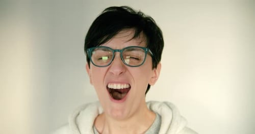 Close up of young woman and with glasses and short hair is tired and yawning