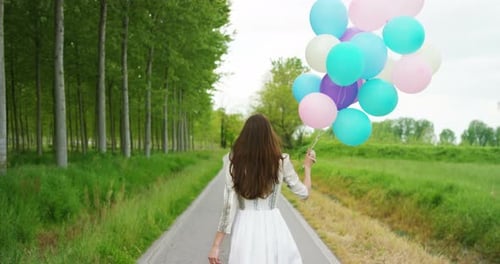 Woman Carries Balloons Down Countryside Path