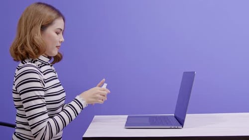 Woman Using Hand Sanitizer Before Typing on Laptop