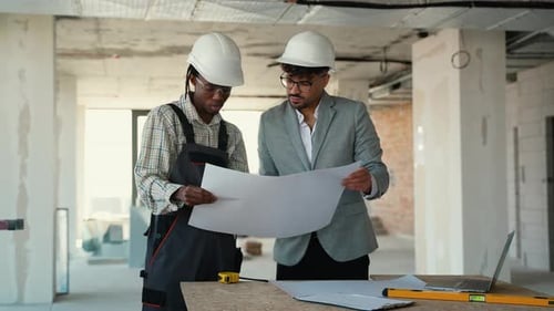 Architects Discussing Blueprints on Construction Site