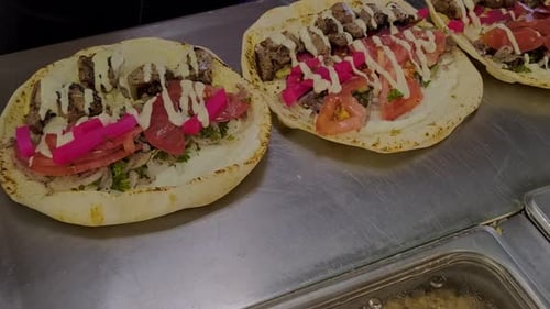 closeup zoom into pita wrap kebab shish shawarma lamb beef sandwiches being made at kitchen of a fas