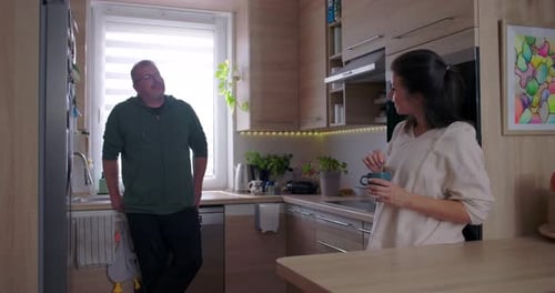 Woman Stirring Drink, Man Standing in Kitchen