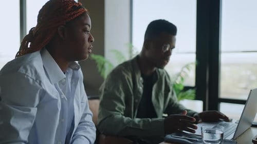 Two Young Black Entrepreneurs Discussing Marketing Strategy in Lively Cafe Setting