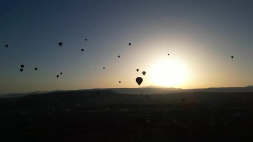 Hot Air Balloons Flying at Sunrise Over Landscape
