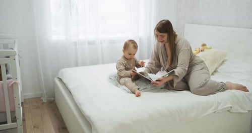 Woman Reading a Book to Her Baby at Home