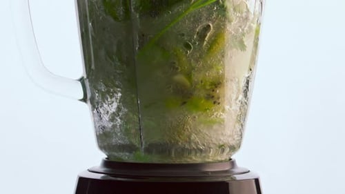 Preparing healthy green vitamin smoothie with electric blender in super slow motion