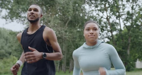 Two fit people running in a park, enjoying their daily exercise and fitness routine outdoors