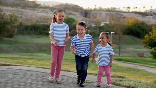Three happy latino mexican kids jumping playing and enjoying smiling in the park on a beautiful day