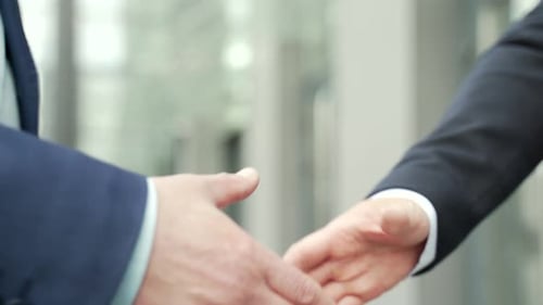 Close up business people shaking hands partnership deal while standing outside on the street near