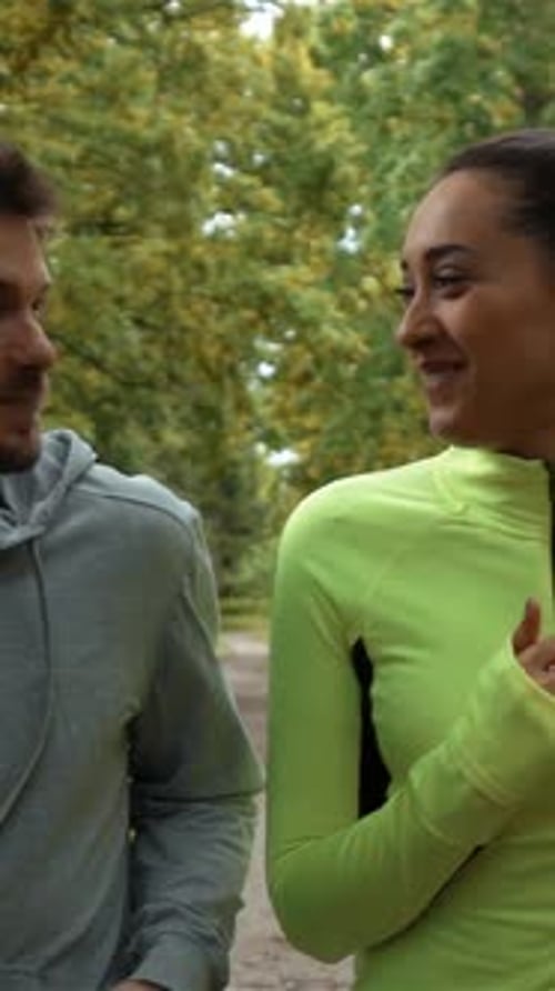 Vertical of Young Male and Feemale Communicating and Smiling During Morning Jog They Running at the