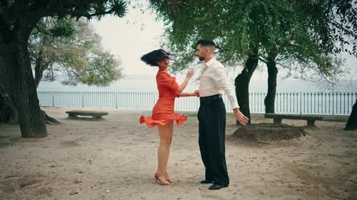 Young professional dancers performing salsa in city park on a summer day