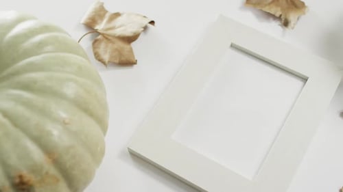 Empty frame with copy space, pumpkin and autumn leaves against white background