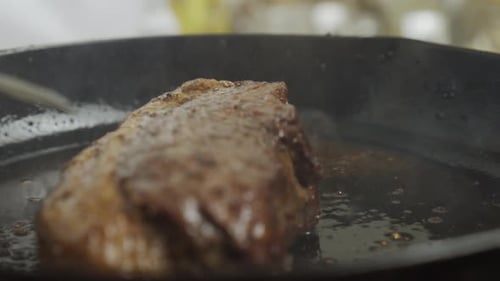 Chef turns frying steak from one side to another. Frying steak in frying pan. Close up slow motion s