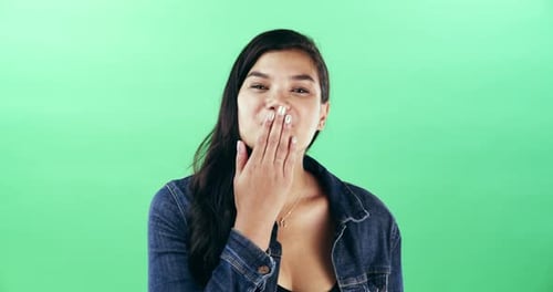 A young woman blowing a kiss against a green studio background