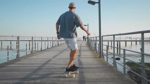 Male Skateboarder Riding Across Bridge