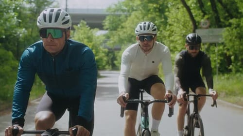Männliche Radfahrer in Sportkleidung fahren moderne Fahrräder entlang der Sunny Road