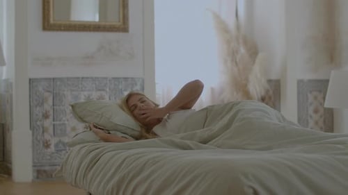 Beautiful Woman Waking Up in Bed Stretching and Yawning