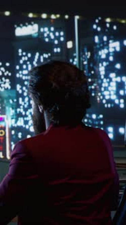 Adult Works on Laptop at Night Overlooking City