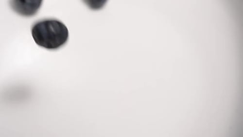 Delicious Blueberries Falling onto White Surface Close Up