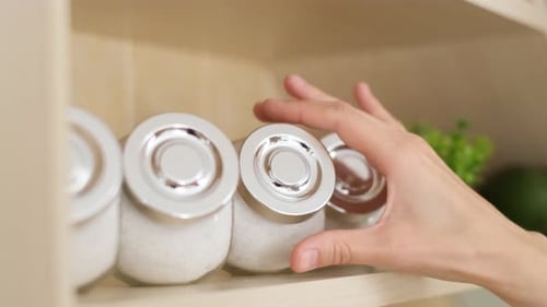 Hand Takes Glass Jar from Kitchen Shelf