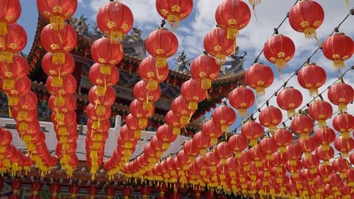 4K Rows of many red traditional Chinese Lantern lamps moving in the wind with the sky and temple