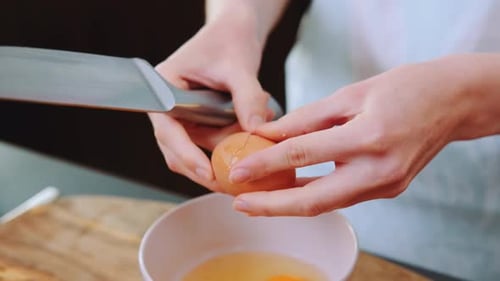 Hands Crack Fresh Eggs into Bowl with Knife