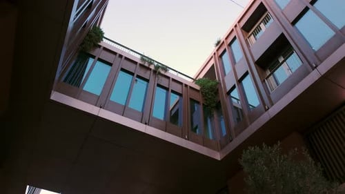 Bottomup View of a Modern Building with a Walkway and Large Floortoceiling Windows