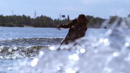 Young man wakeboarding behind motorboat on river training for competition