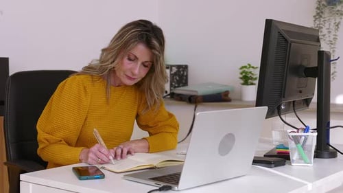Businesswoman Working From Home Office Taking Notes and Using Laptop