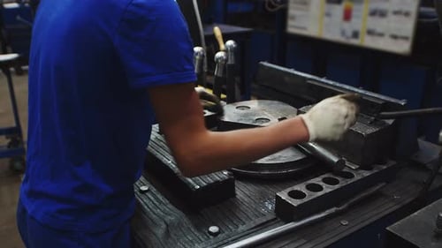 Mann im Overall nähert sich der Fabrikmaschine mit Metall, Partei legt Teil auf Maschine und bearbeitet es