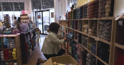 Female Business Owner with Laptop Reing Yarn in Yarn Store