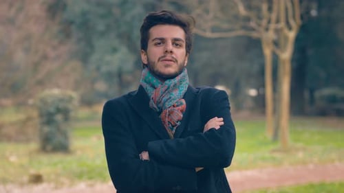 young man at park looking at camera and crossing his arms