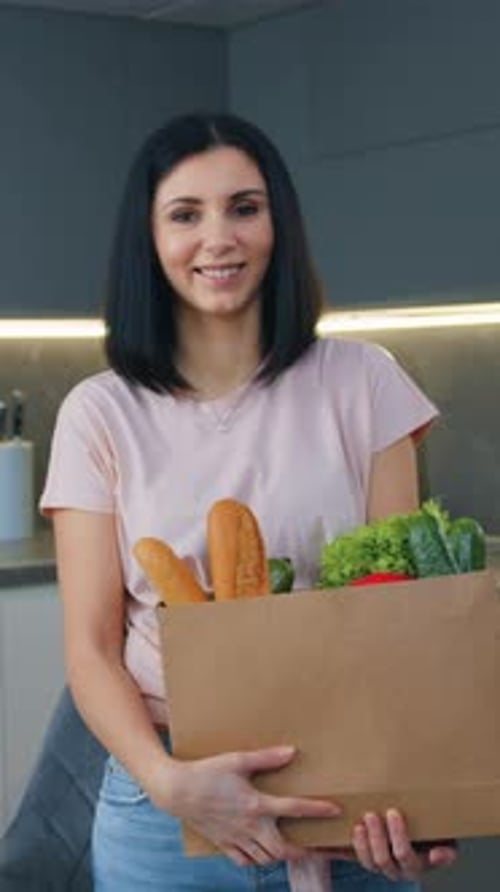 Goodlooking Smiling Satisfied 30Aged Brunette Posing on Camera with Products Paper Bag Full of Green